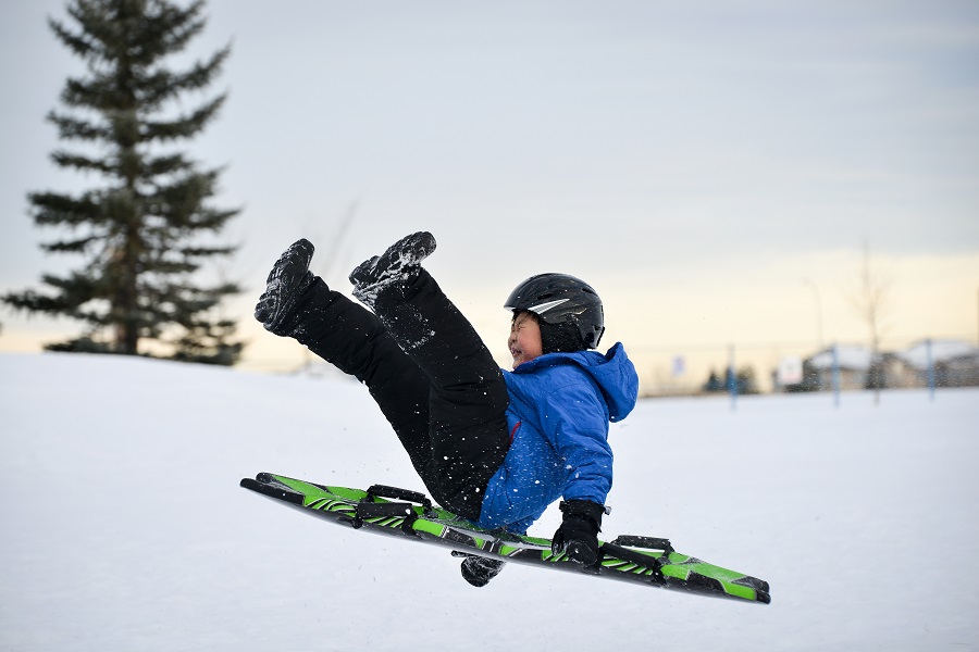 boy wearing helmet sledding following winter safety tips