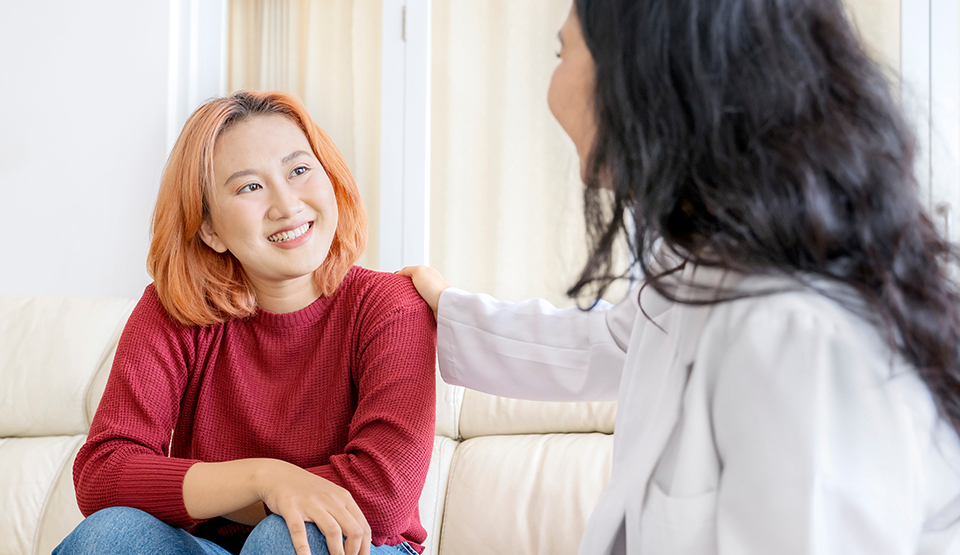 An adult counsels a child and touches her shoulder in a caring gesture.