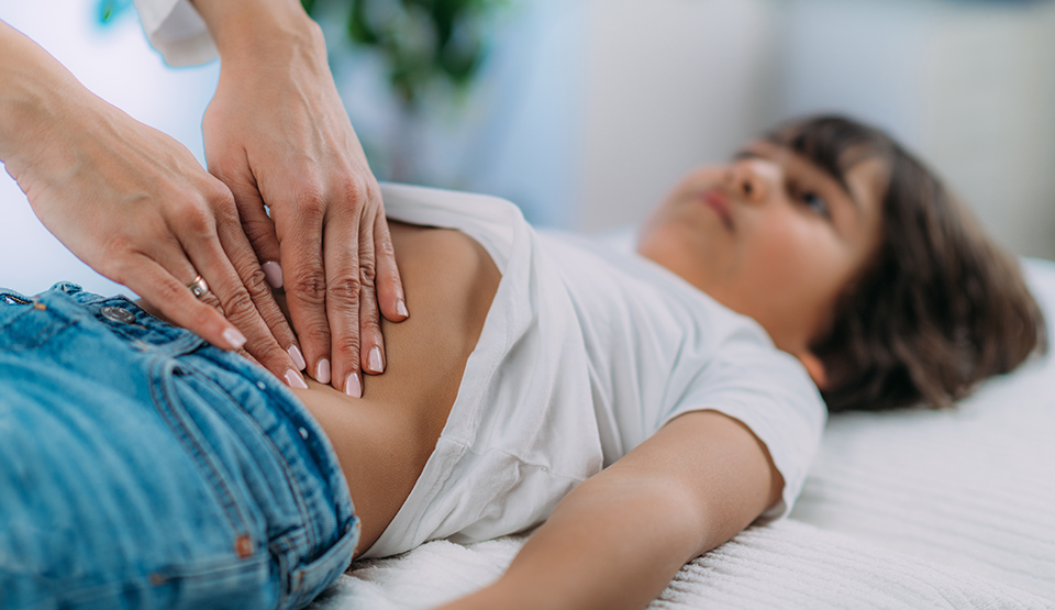 A doctor presses on a child's abdomen during an examination.