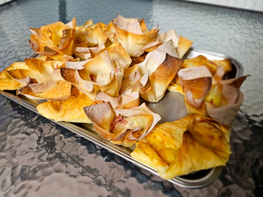 A tray featuring ham and cheese wontons on a table.