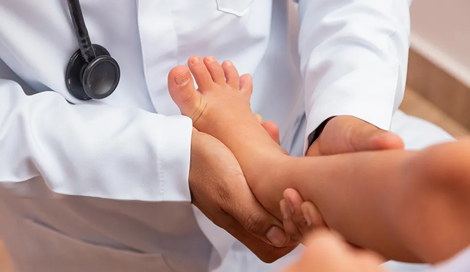 A doctor examines a young patient's ankle.