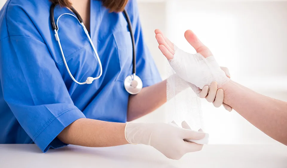 A health care worker wraps a patients hand wound.