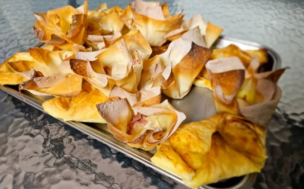 A tray featuring ham and cheese wontons on a table.